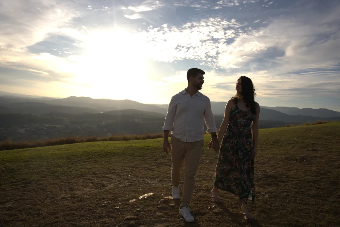 Casal caminhando de mãos dadas no campo ao pôr do sol